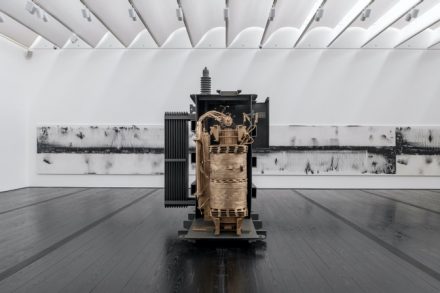 Front: Allora & Calzadilla, Blackout, 2020. Power transformer, bronze, electricity, vocalists, 120 1/2 × 85 1/2 × 78 3/4 inches. Courtesy of Lisson Gallery, New York and London. Rear: Allora & Calzadilla, Cadastre (Meter Number 18257262, Consumption Charge 36.9kWh x $0.02564, Rider FCA-Fuel Charge Adjusted 36.9 kWh x $0.053323, RiderPPCA-Purchase Power Charge Adjusted 36.9kWh x $0.016752, Rider CILTA-Municipalities Adjusted 36.9kWh x $0.002376, Rider SUBA subsidies $1.084), 2019. Iron filings on linen, overall: 72 × 840 inches, each: 72 × 120 inches. Courtesy of Gladstone Gallery, New York and Brussels. © Allora & Calzadilla. Photo: Paul Hester.